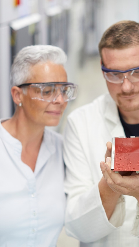 Three employees in different work clothes checking a painted panel Three employees in different work clothes checking a painted panel