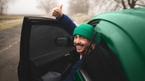 Man with green cap looking out of the car and holding his thumb up Man with green cap looking out of the car and holding his thumb up