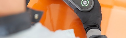 Two hands holding a spectrophotometer on an orange car