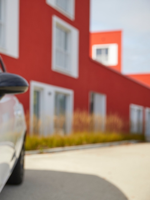 White car in front of a red building