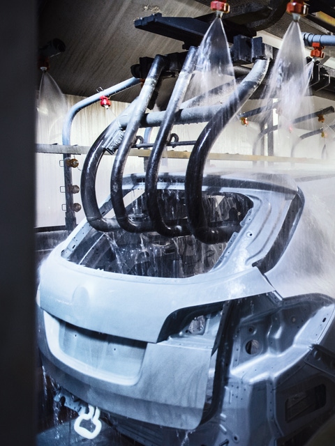 Car bodies being cleaned prior to spraying in car factory.