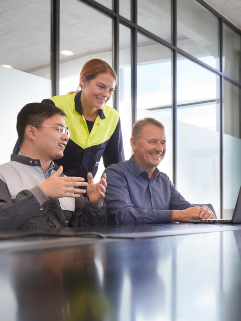 Three employees talking to a colleague on a screen in a virtual meeting