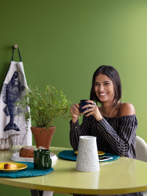 Suvinil lifestyle: Young woman drinking coffee  in a green kitchen.