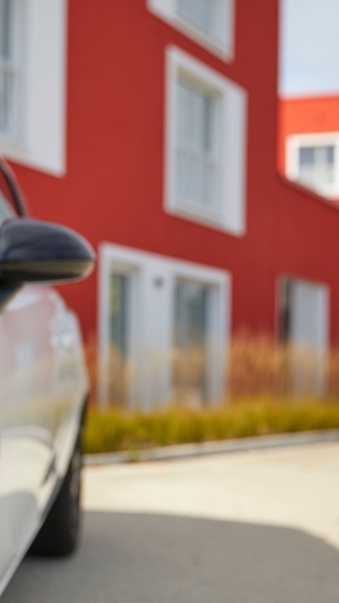 White car in front of a red building