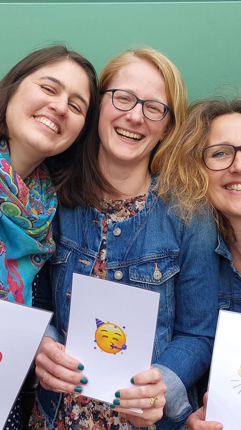 Four women standing close together and laughing 